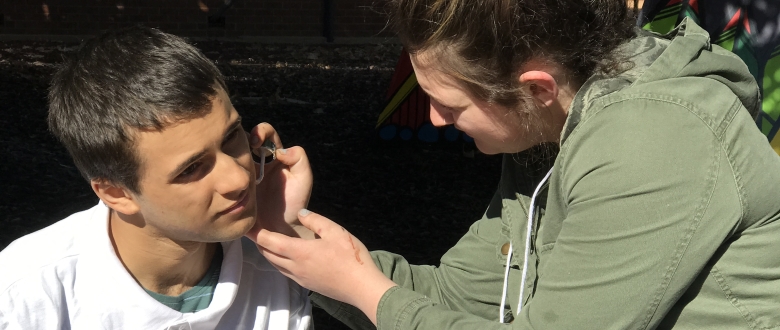 Dayna Behsman applying make-up to actor Jordan Davis on the set of "Zit"